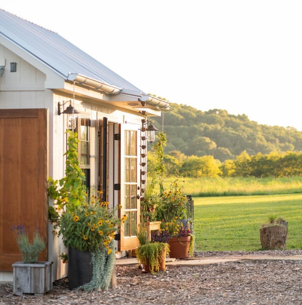 A quaint white shed with a metal roof is nestled in a lush green field at sunset in Williamson County, Tennessee.