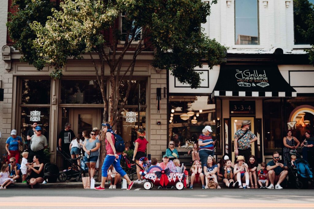 Crowd of people, including families with children, gathered outside a storefront on a sunny day in Williamson County, Tennessee.