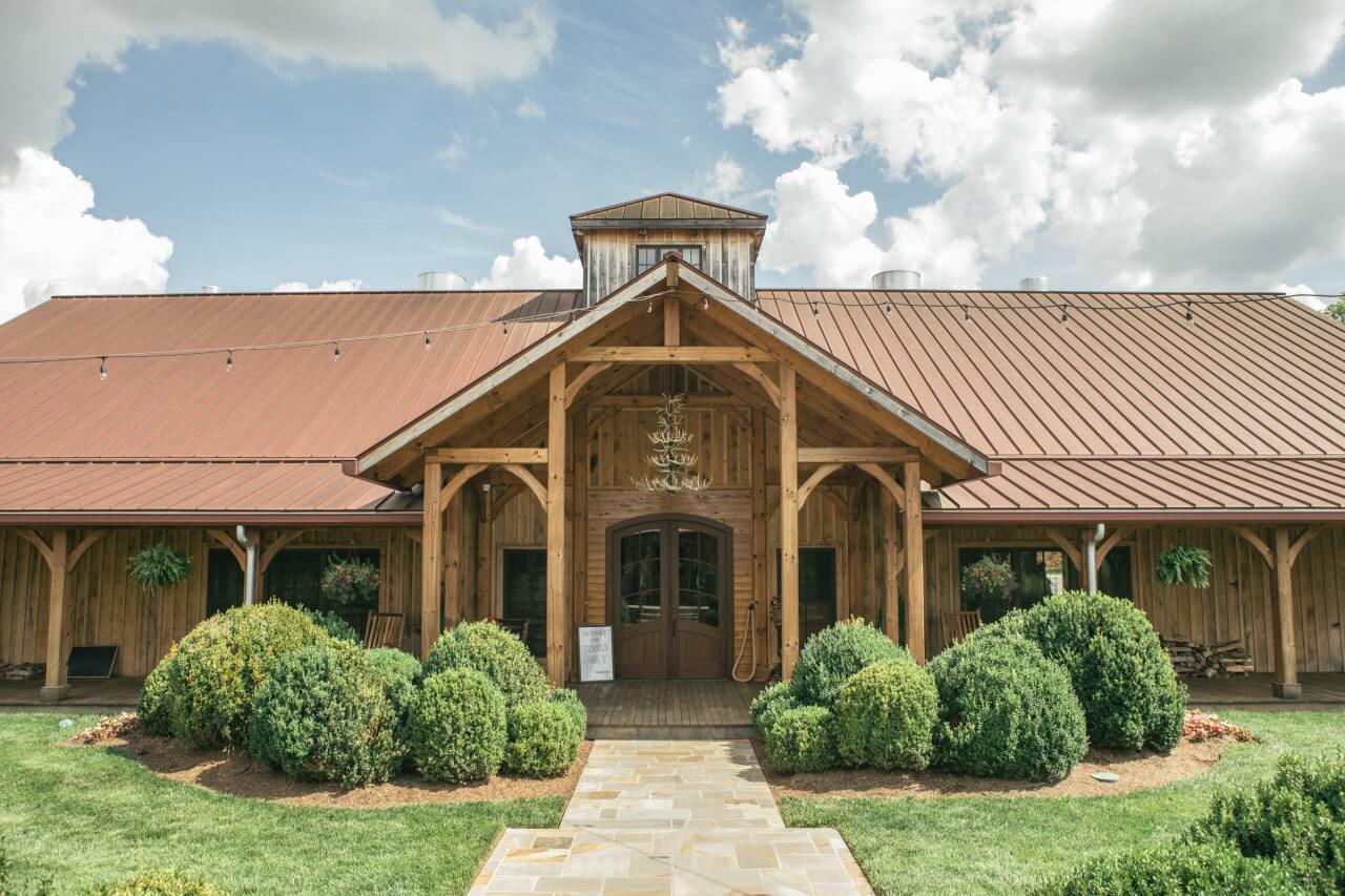 A rustic wooden barn with a red metal roof and a stone walkway leading to the entrance in Williamson County, Tennessee.