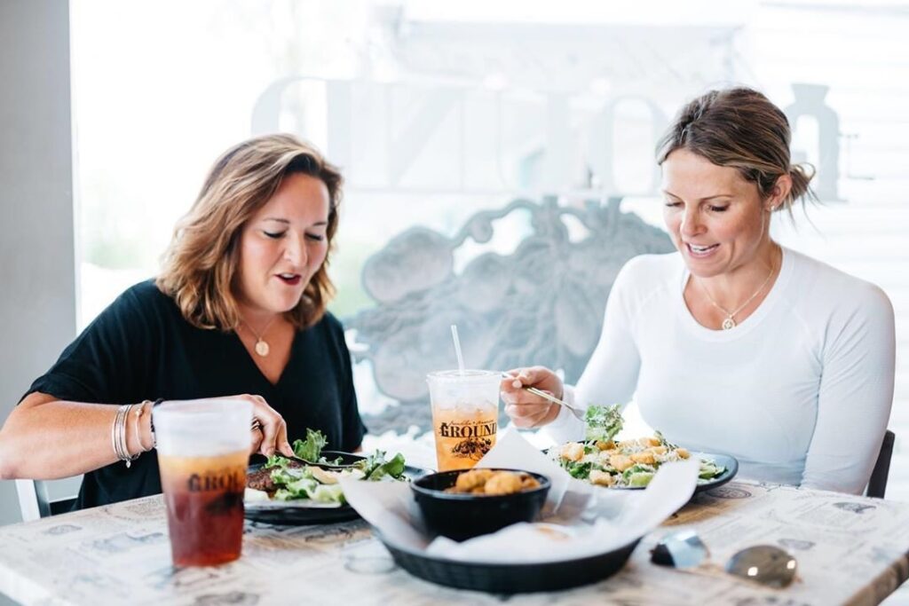Two women enjoying a meal together at a restaurant with salads and iced tea in Williamson County, Tennessee.