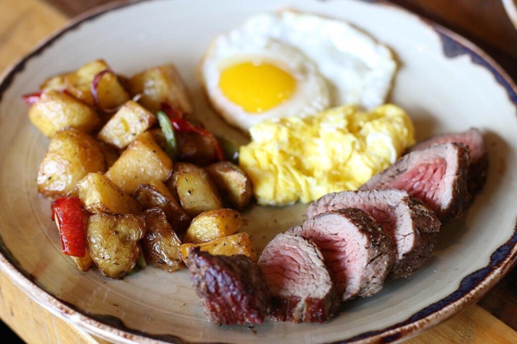 A hearty breakfast plate with steak, potatoes, eggs, and scrambled eggs in Williamson County, Tennessee.