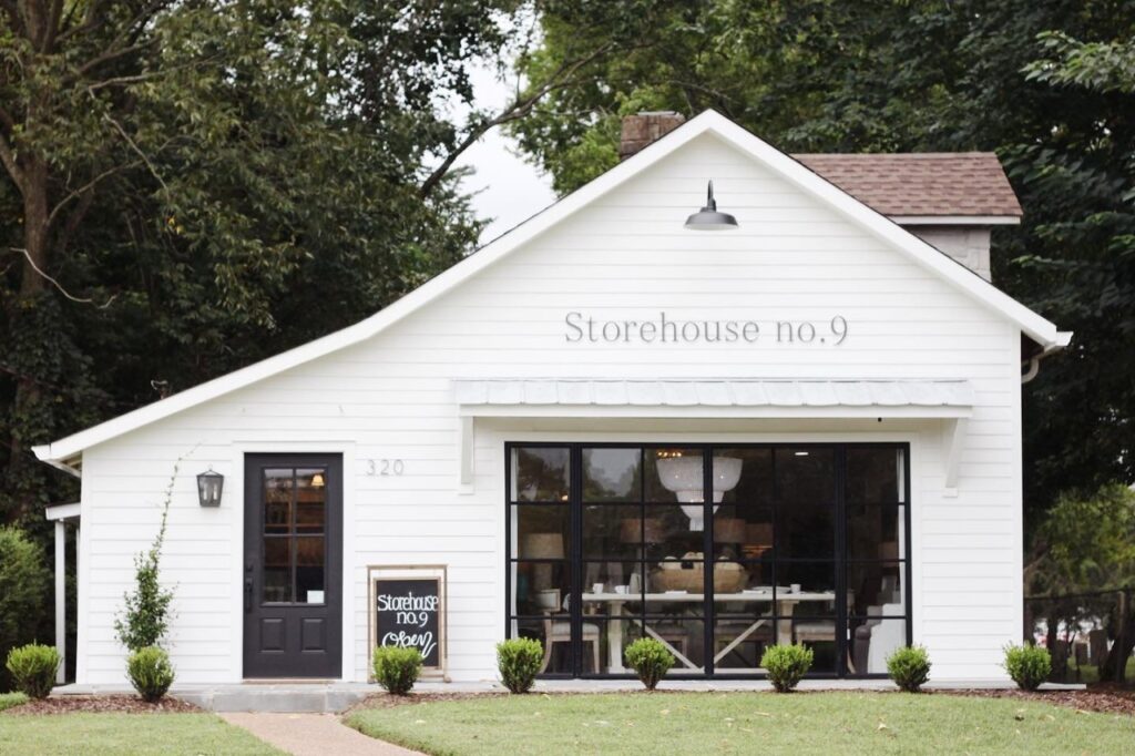 A quaint white storehouse with black trim and large windows, surrounded by greenery in Williamson County, Tennessee.