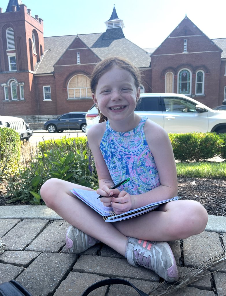 young girl sitting in front of historic church in quaint downtown area