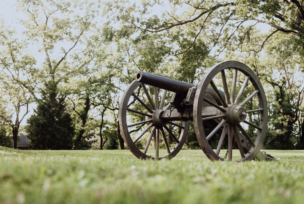 cannon displayed in field at historic site during springtime