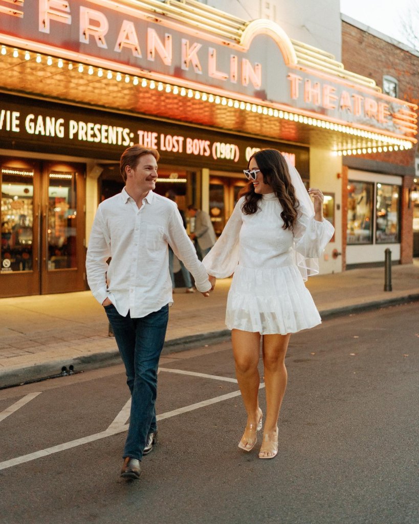 couple holding hands walking in front of historic theater on Main Street