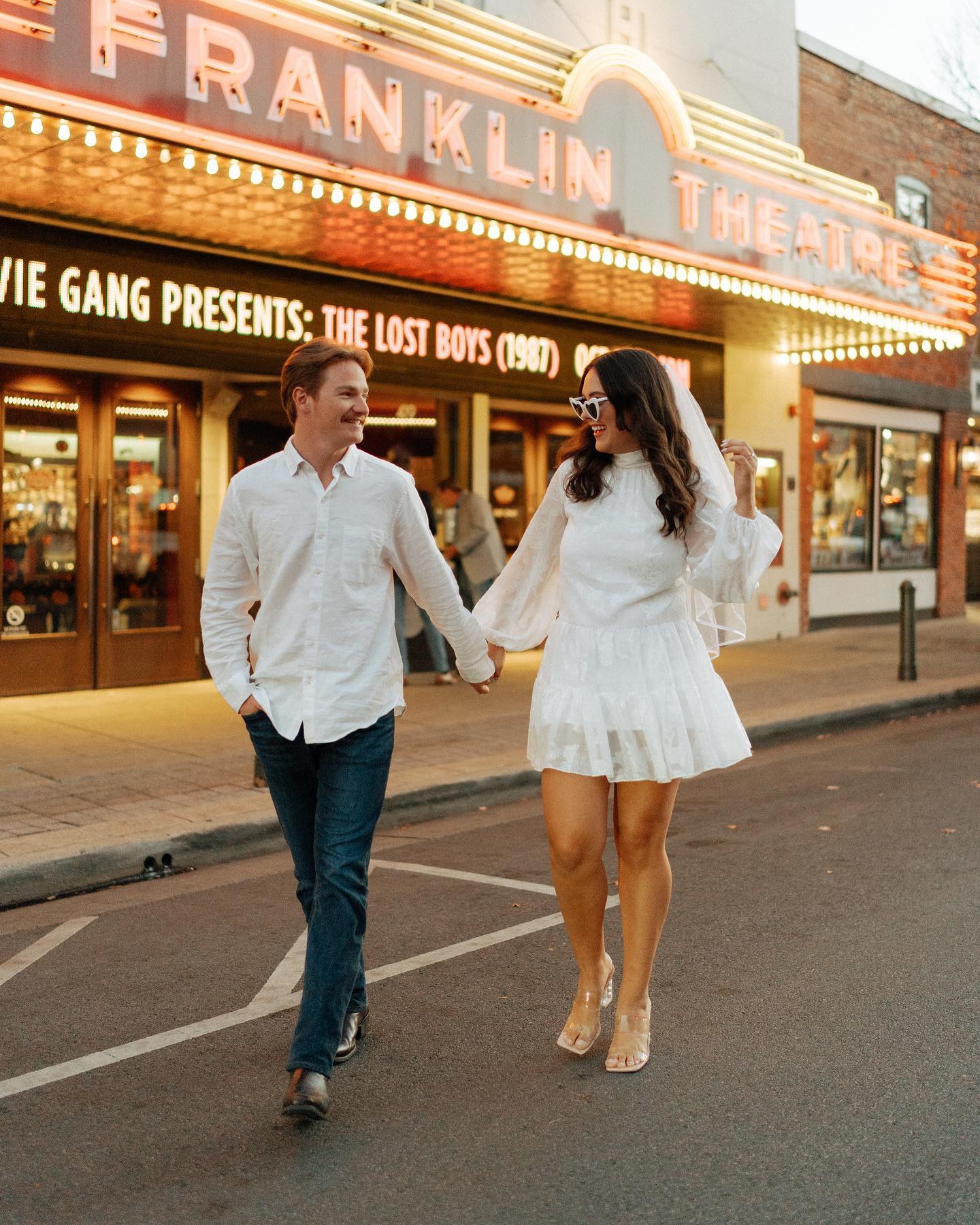 couple holding hands walking in front of historic theater on Main Street