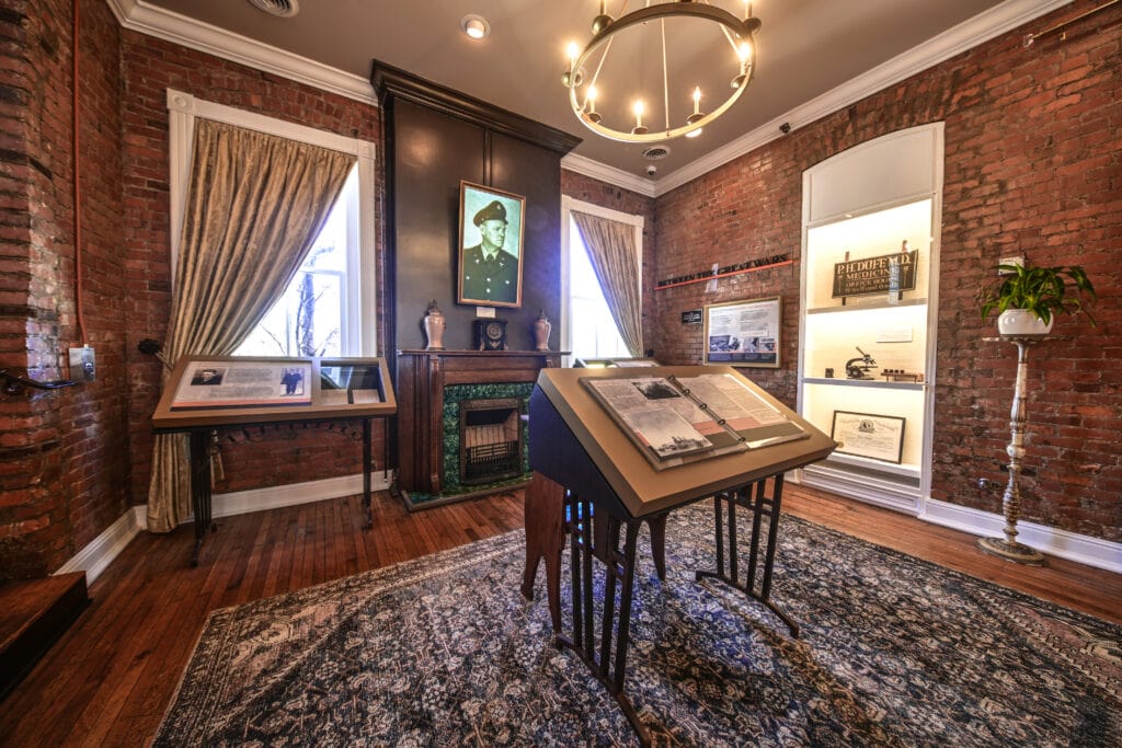 A museum room with brick walls, a chandelier, and historical exhibits including a portrait and documents in Williamson County, Tennessee.