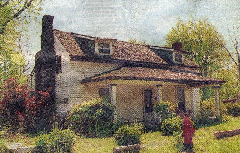 A dilapidated white farmhouse with a shingled roof and a red fire hydrant in the yard in Williamson County, Tennessee.