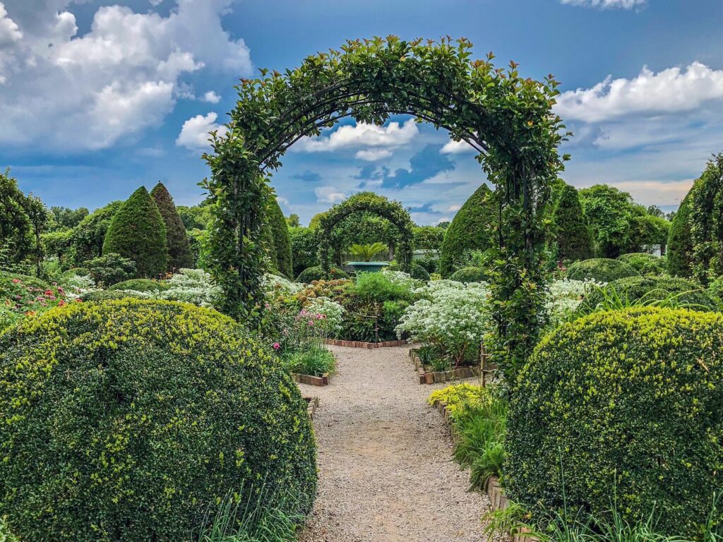 A gravel path winds through a lush garden with neatly trimmed hedges and arches in Williamson County, Tennessee.