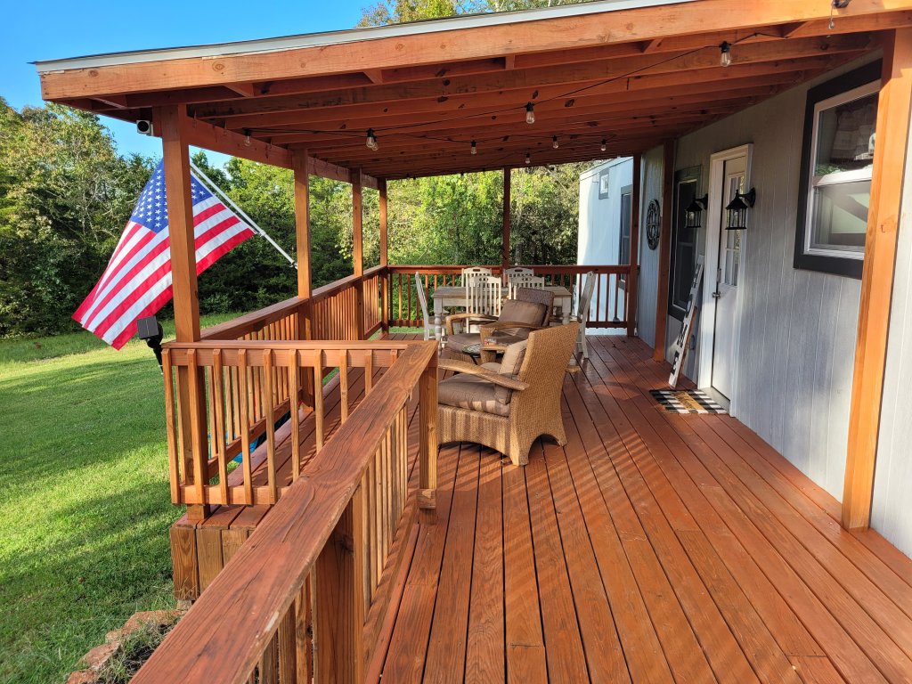 A wooden deck with a covered porch area, outdoor furniture, and an American flag in Williamson County, Tennessee.