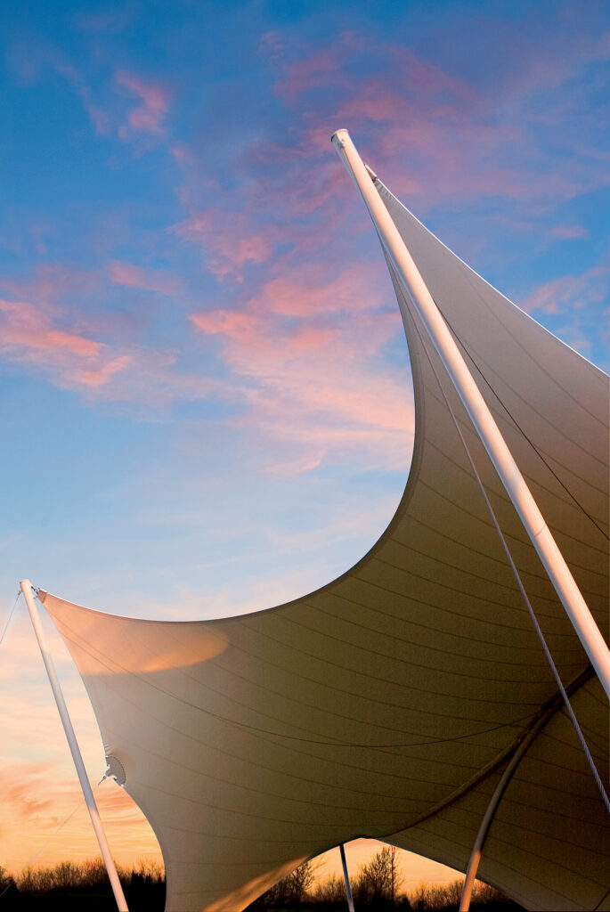 Two large, curved white sails stretch across the sky, silhouetted against a colorful sunset in Williamson County, Tennessee.