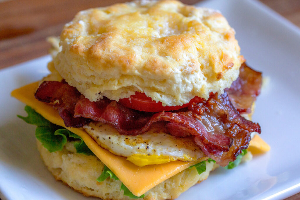 A mouthwatering breakfast sandwich with bacon, egg, cheese, and tomato between two golden biscuits in Williamson County, Tennessee.