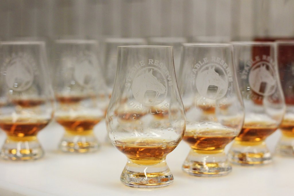 A row of branded whiskey tasting glasses filled with amber liquid on a white surface in Williamson County, Tennessee.