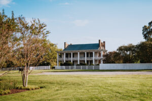 A white two-story house with a porch and columns stands in a grassy field with trees in Williamson County, Tennessee.