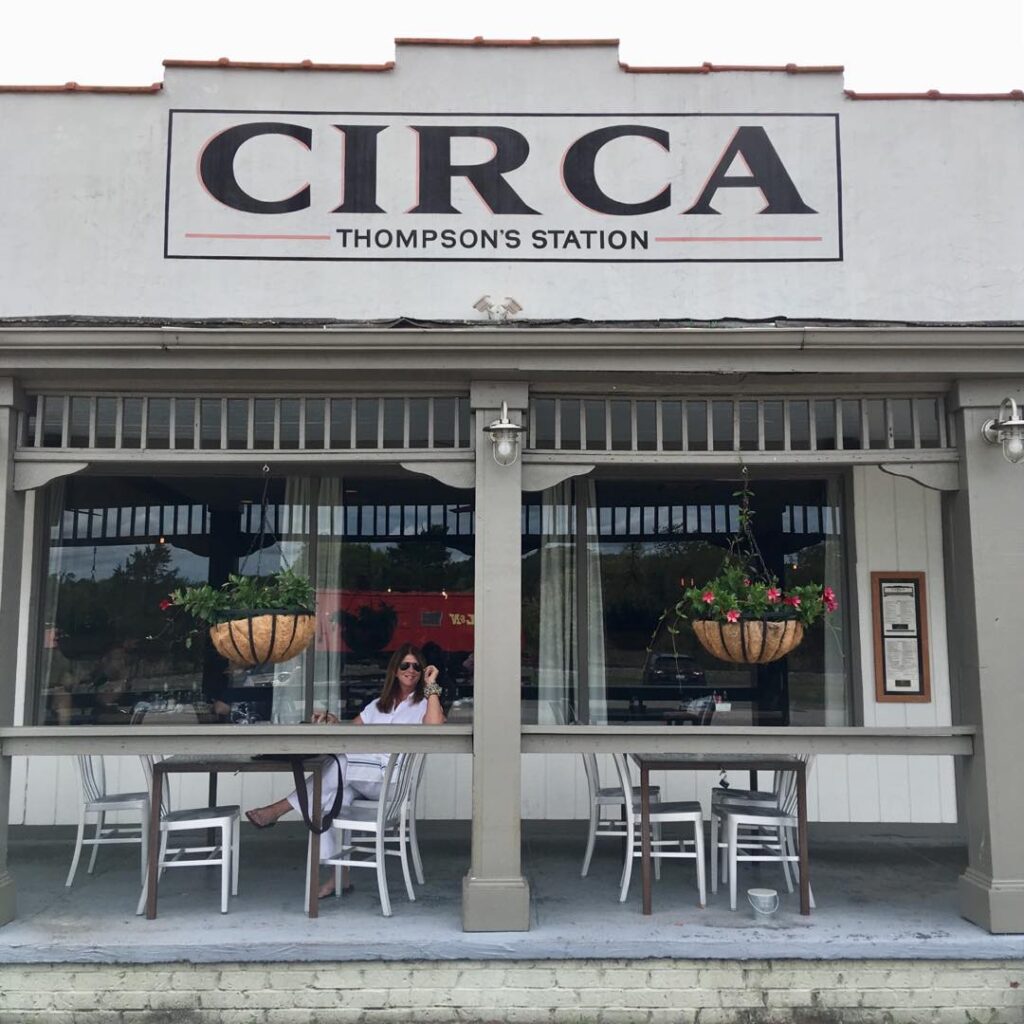 Woman sits on porch of Circa Thompson's Station restaurant, enjoying sunny day in Williamson County, Tennessee.
