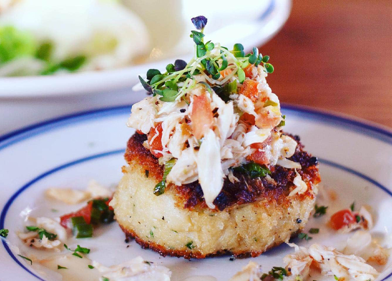A golden-brown crab cake topped with a colorful mix of crab meat, tomatoes, and herbs in Williamson County, Tennessee.