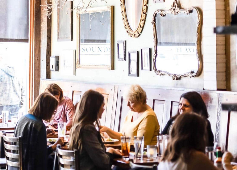 A group of women are gathered around a table in a cozy restaurant with vintage decor in Williamson County, Tennessee.