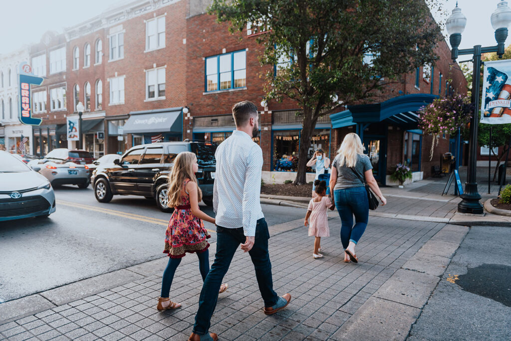 10 Must-Do Activities for Franklin Visitors A family of four walks down a brick-paved street lined with shops and parked cars in Williamson County, Tennessee.