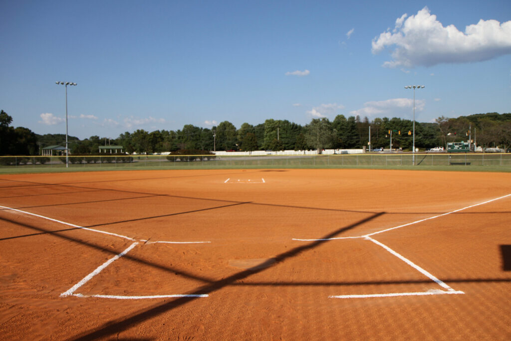 A well-maintained baseball diamond with white chalk lines on a red clay field under a clear blue sky in Williamson County, Tennessee.