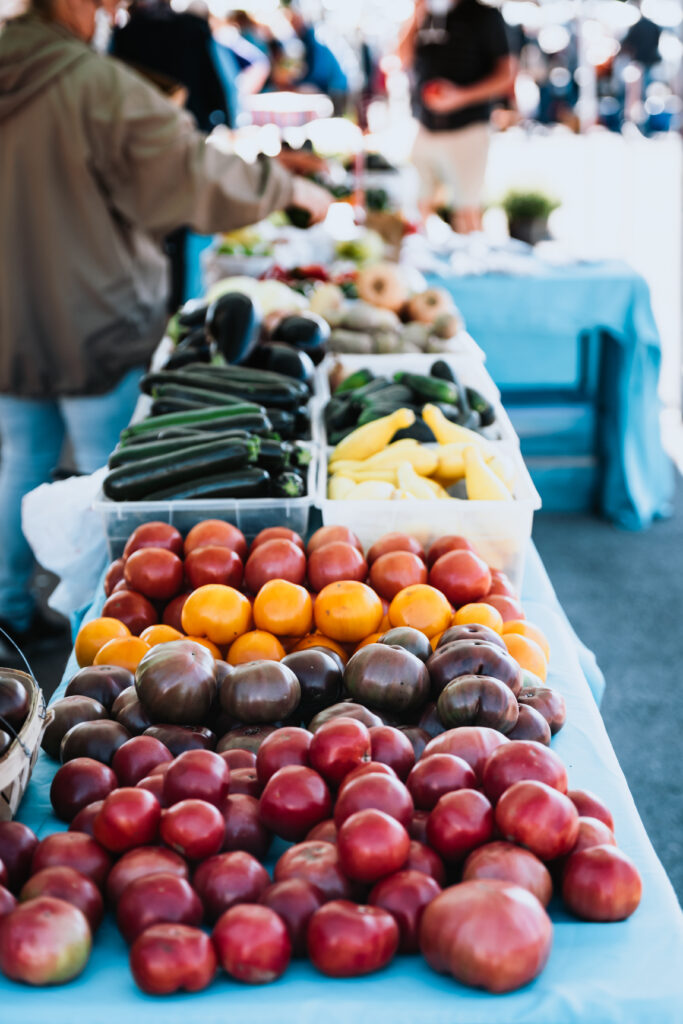 A vibrant farmer's market table displays a colorful array of fresh produce, including tomatoes, zucchini, and eggplants in Williamson County, Tennessee.