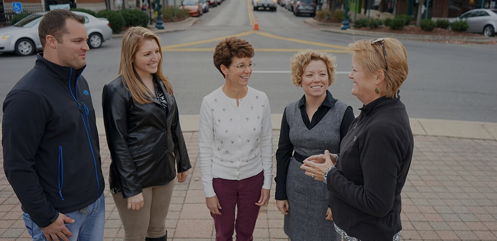 Five people, three women and two men, are standing and smiling on a city sidewalk in Williamson County, Tennessee.