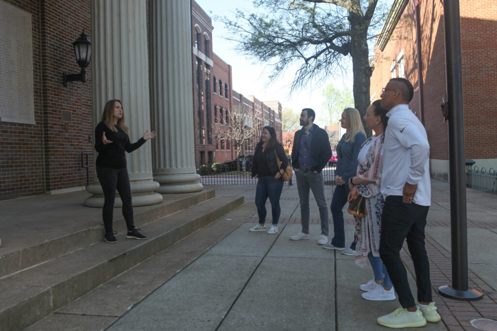 A group of people are gathered on a sidewalk in front of a building with columns in Williamson County, Tennessee.