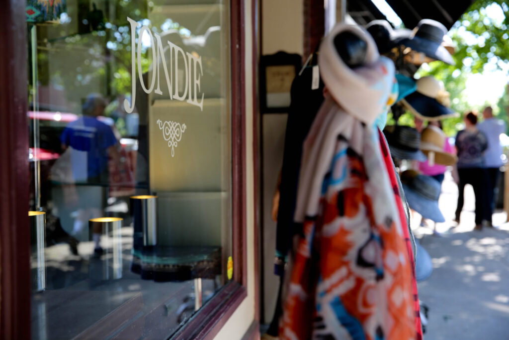 A colorful scarf hangs in a shop window next to a sign reading 'Jondie' in Williamson County, Tennessee.