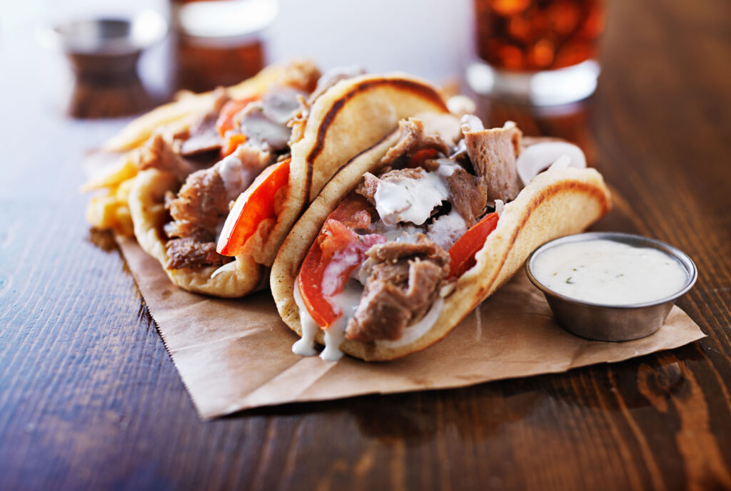 Three delicious gyros with meat, tomatoes, and tzatziki sauce on a wooden table in Williamson County, Tennessee.