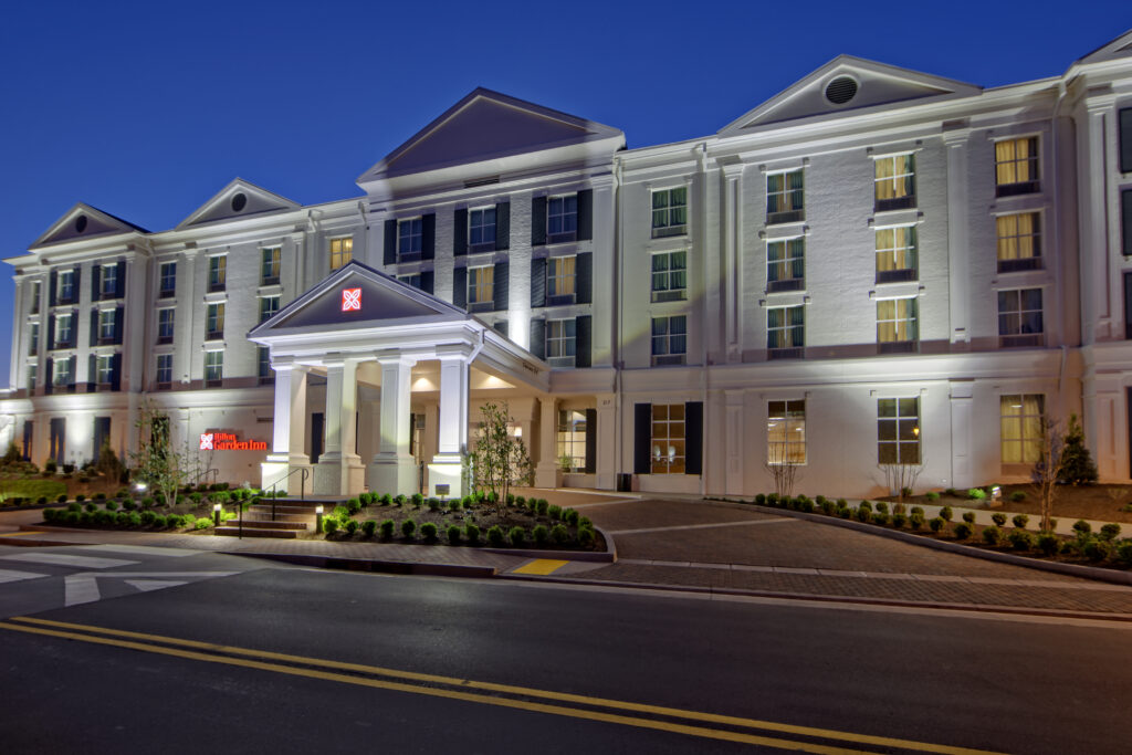 A large, white hotel with columns and a red sign, illuminated at night in Williamson County, Tennessee.