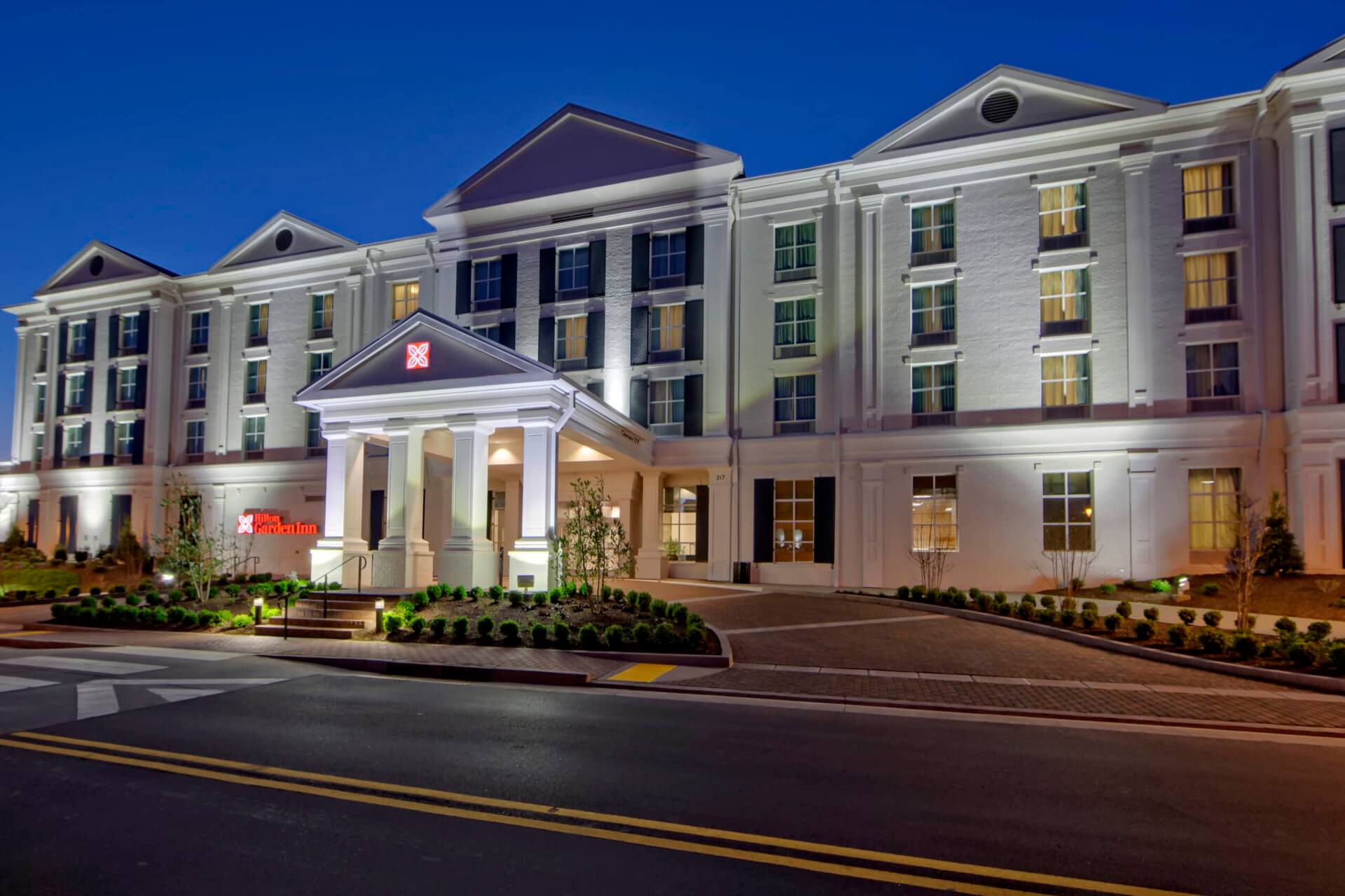 A large, white hotel with columns and a red sign, illuminated at night in Williamson County, Tennessee.