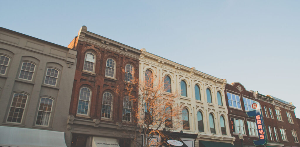 7 Surprising Facts You'll Learn on a Franklin Walking Tour! A row of historic buildings with ornate facades and large windows, bathed in warm sunlight in Williamson County, Tennessee.