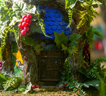 A whimsical treehouse door, adorned with vibrant red berries and lush greenery, invites visitors to enter a magical forest realm in Williamson County, Tennessee.