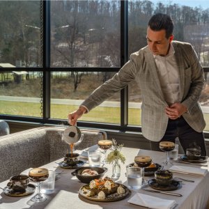 A man in a suit pours coffee at a table set with various dishes and drinks in Williamson County, Tennessee.