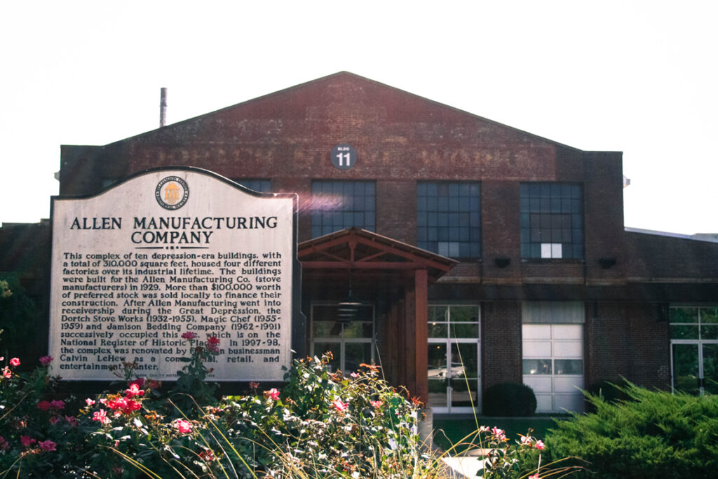 A historic brick building with a sign for Allen Manufacturing Company in front of it in Williamson County, Tennessee.