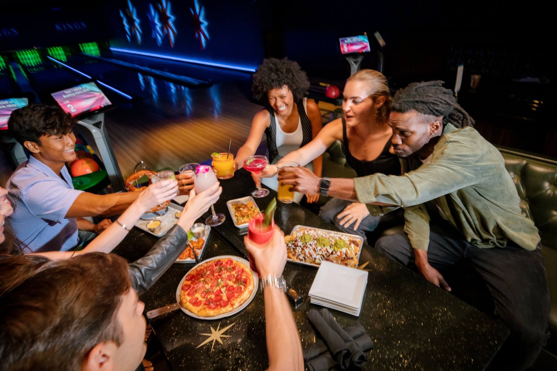 A group of friends celebrates with drinks and pizza at a bowling alley in Williamson County, Tennessee.