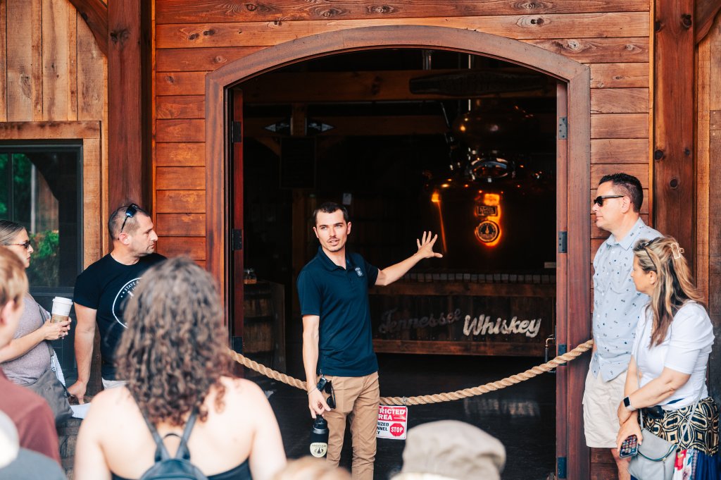 Group of people gather outside a wooden building with a sign reading 'Tennessee Whiskey' in Williamson County, Tennessee.