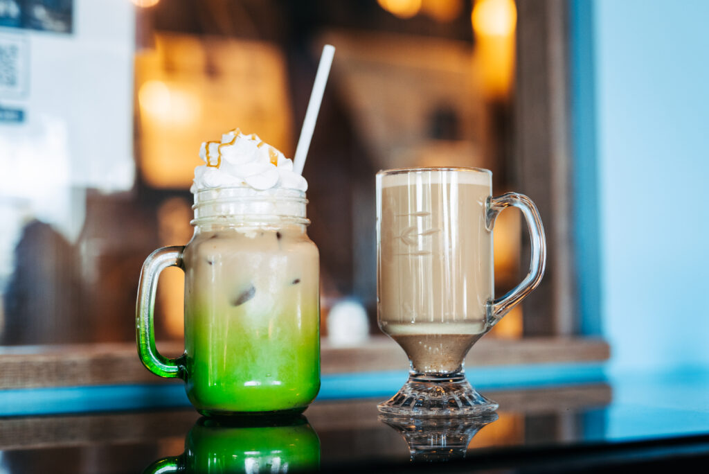 Two colorful coffee drinks with whipped cream sit on a reflective surface in Williamson County, Tennessee.
