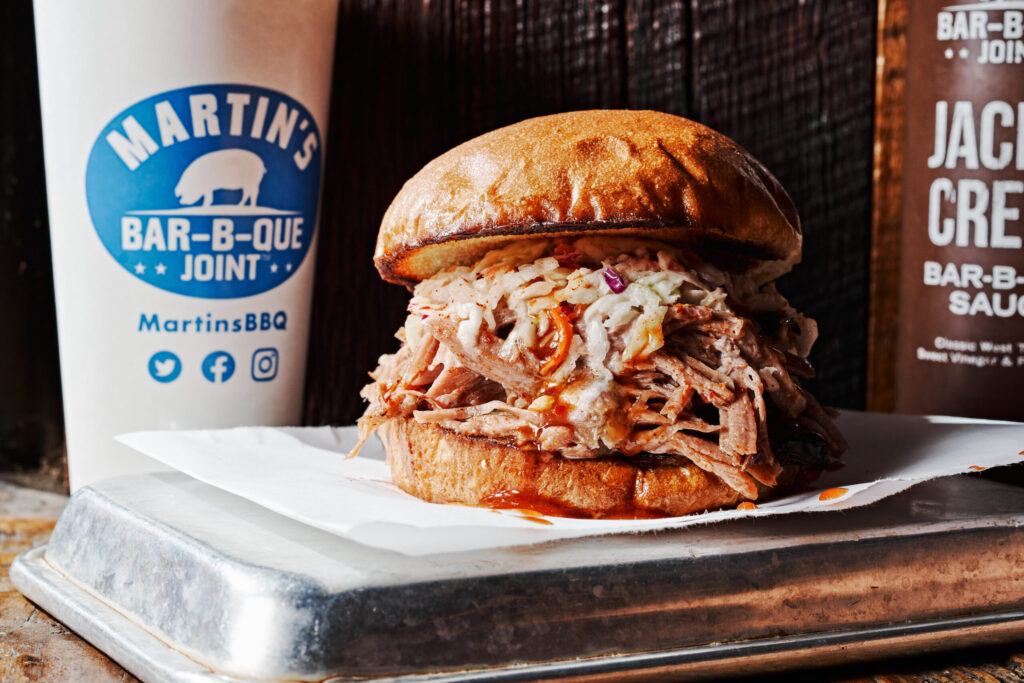 A mouthwatering pulled pork sandwich with coleslaw on a toasted bun, served on a metal tray in Williamson County, Tennessee.