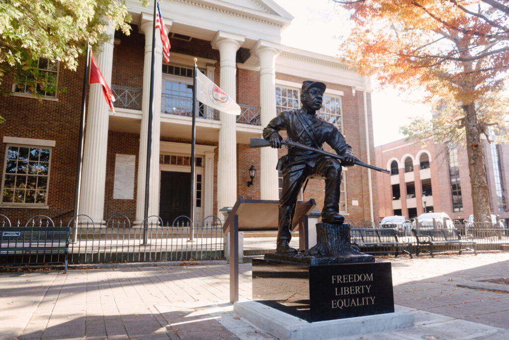 A bronze statue of a soldier with a rifle stands on a pedestal inscribed with 'Freedom, Liberty, Equality' in Williamson County, Tennessee.
