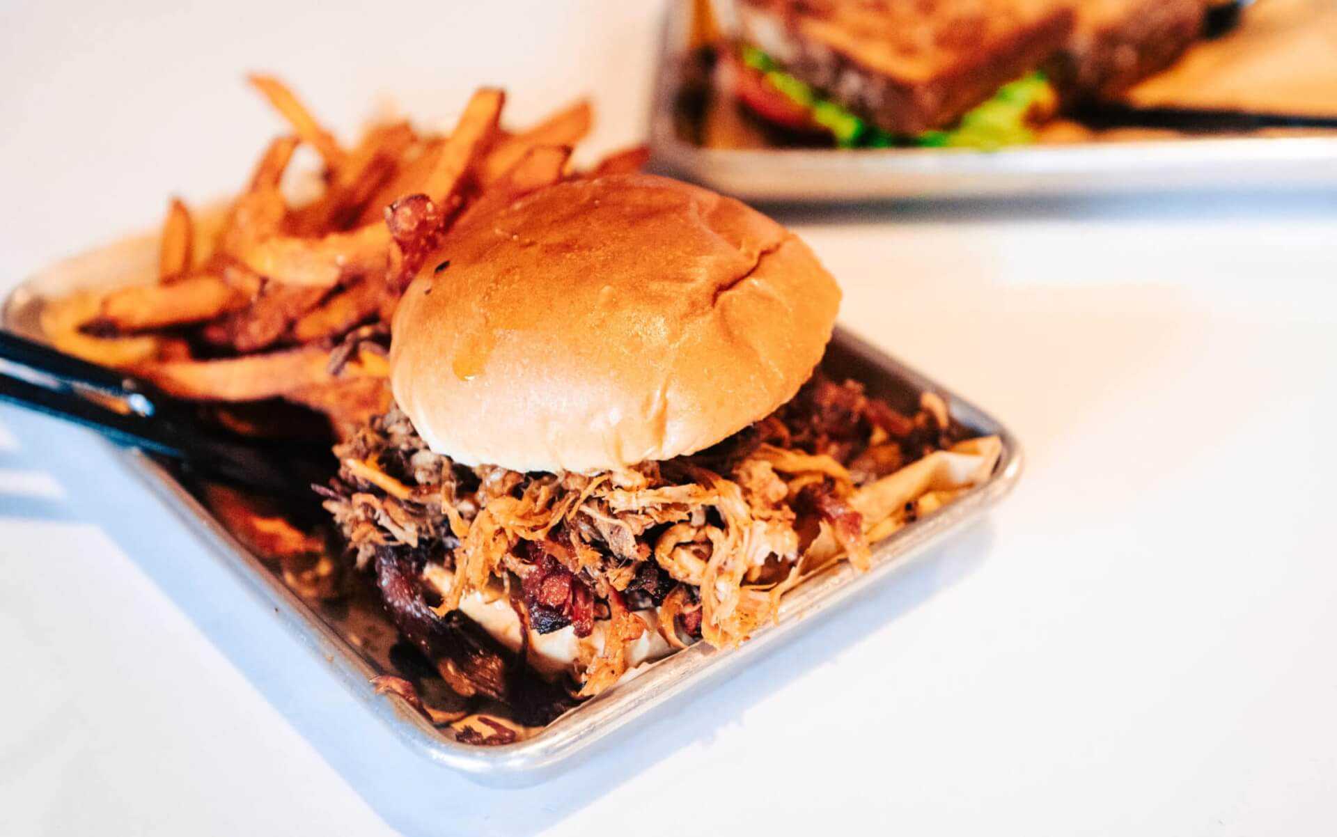A mouthwatering pulled pork sandwich with crispy fries on a metal tray in Williamson County, Tennessee.
