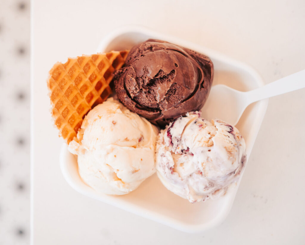 A square white dish holds three scoops of ice cream: chocolate, vanilla, and strawberry, with a waffle cone in Williamson County, Tennessee.