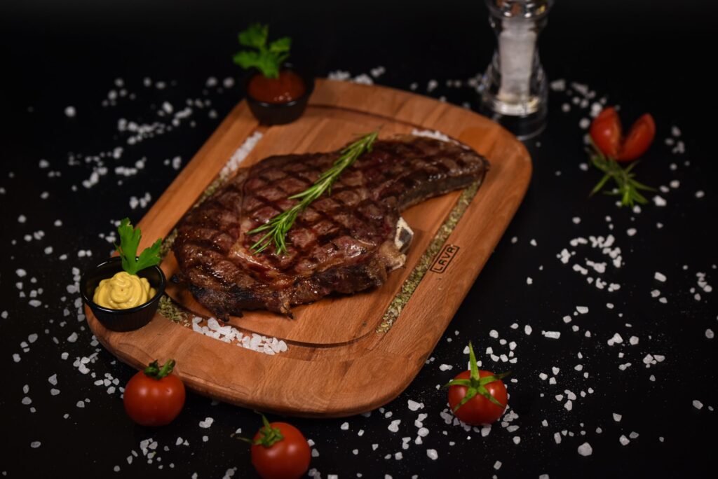 A juicy steak with rosemary garnish on a wooden board, served with mustard and tomatoes in Williamson County, Tennessee.