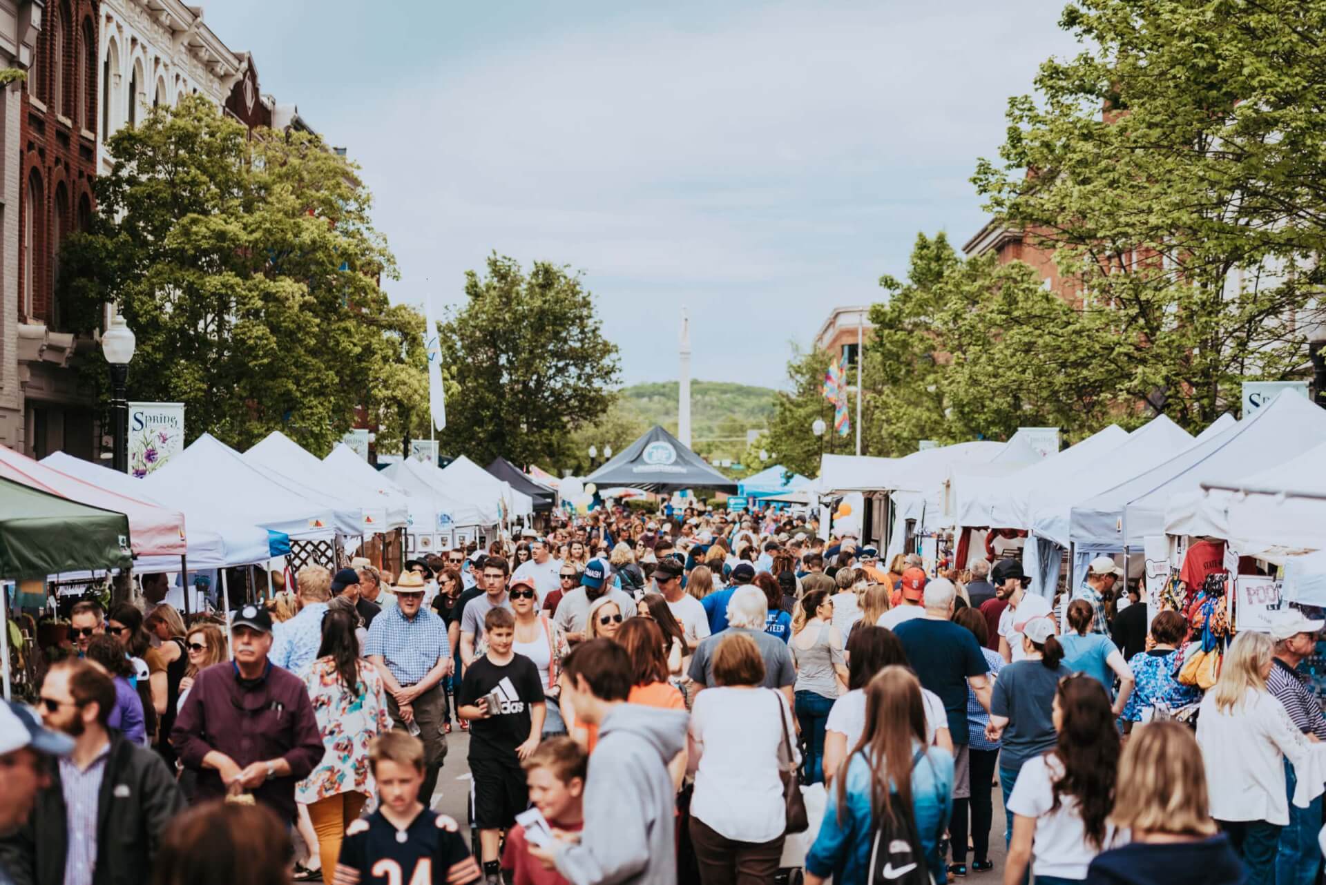 A bustling outdoor market with numerous white tents, filled with people shopping and browsing in Williamson County, Tennessee.