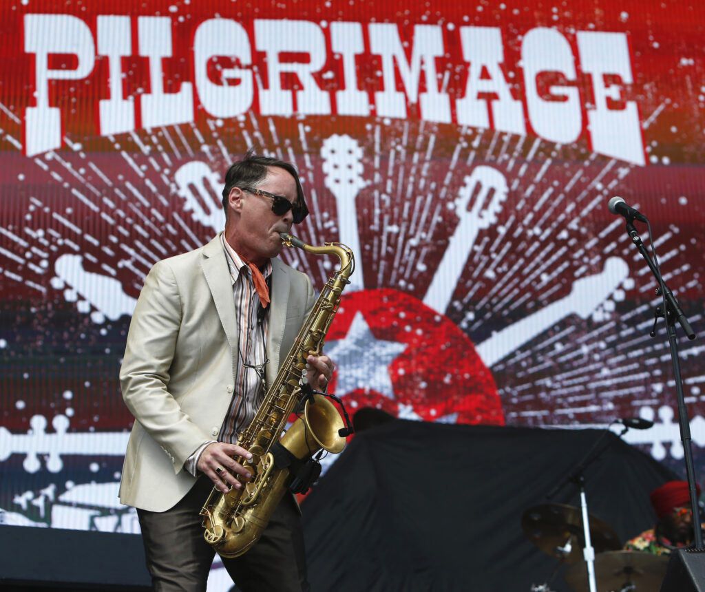 A musician in a white suit plays a saxophone on stage with a colorful backdrop in Williamson County, Tennessee.