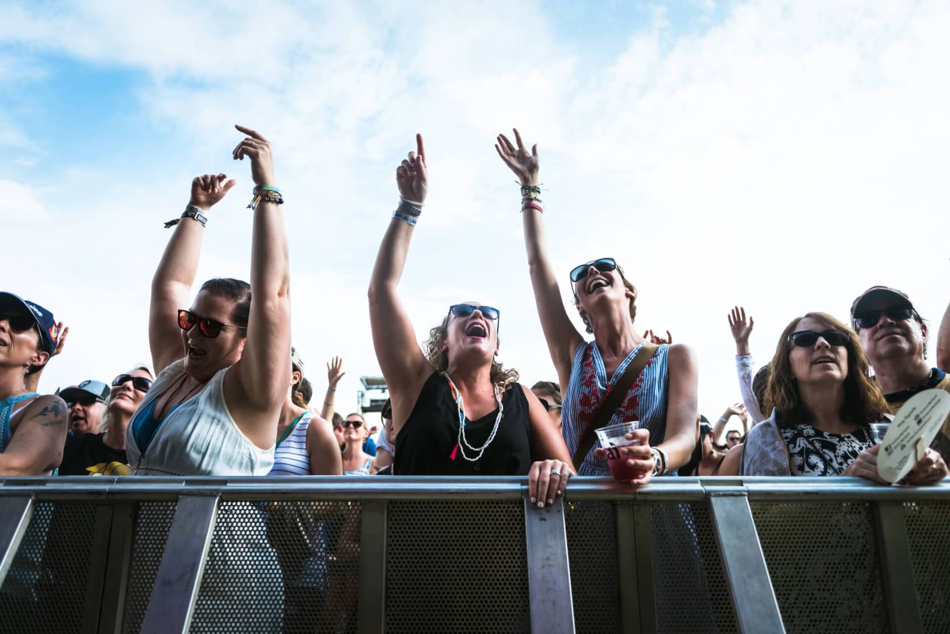 Enthusiastic concertgoers raise their hands in unison, celebrating the music under a clear blue sky in Williamson County, Tennessee.