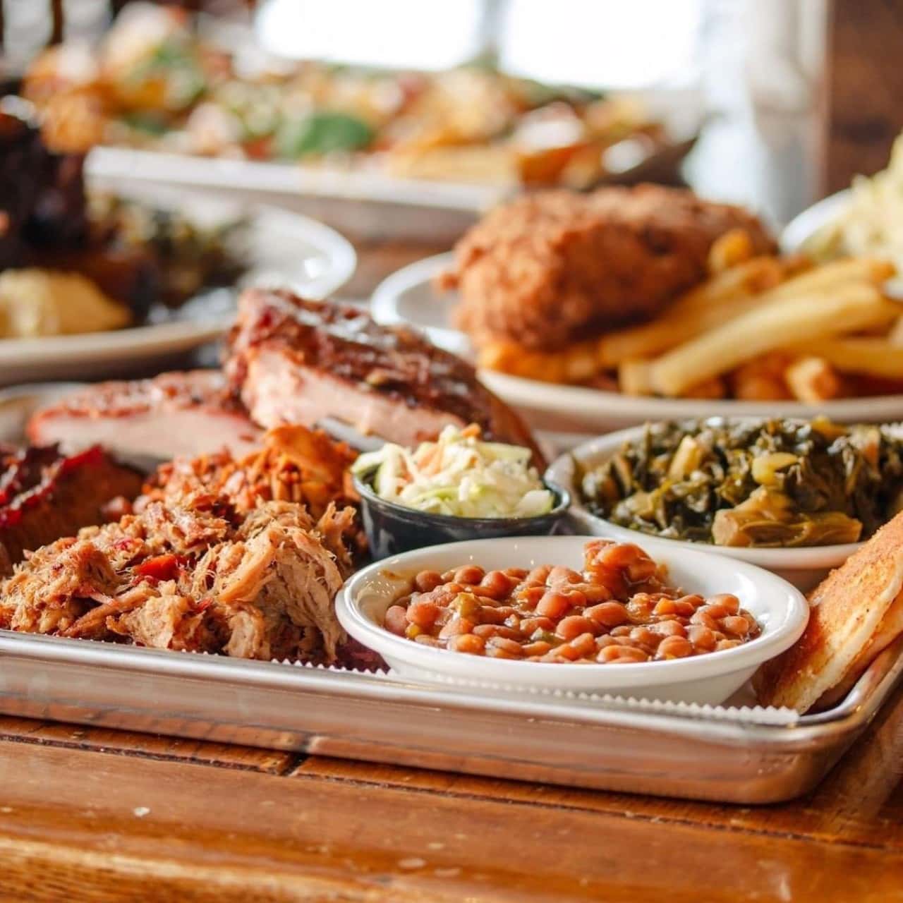 A metal tray holds a variety of barbecue dishes, including pulled pork, ribs, beans, greens, and fried chicken in Williamson County, Tennessee.