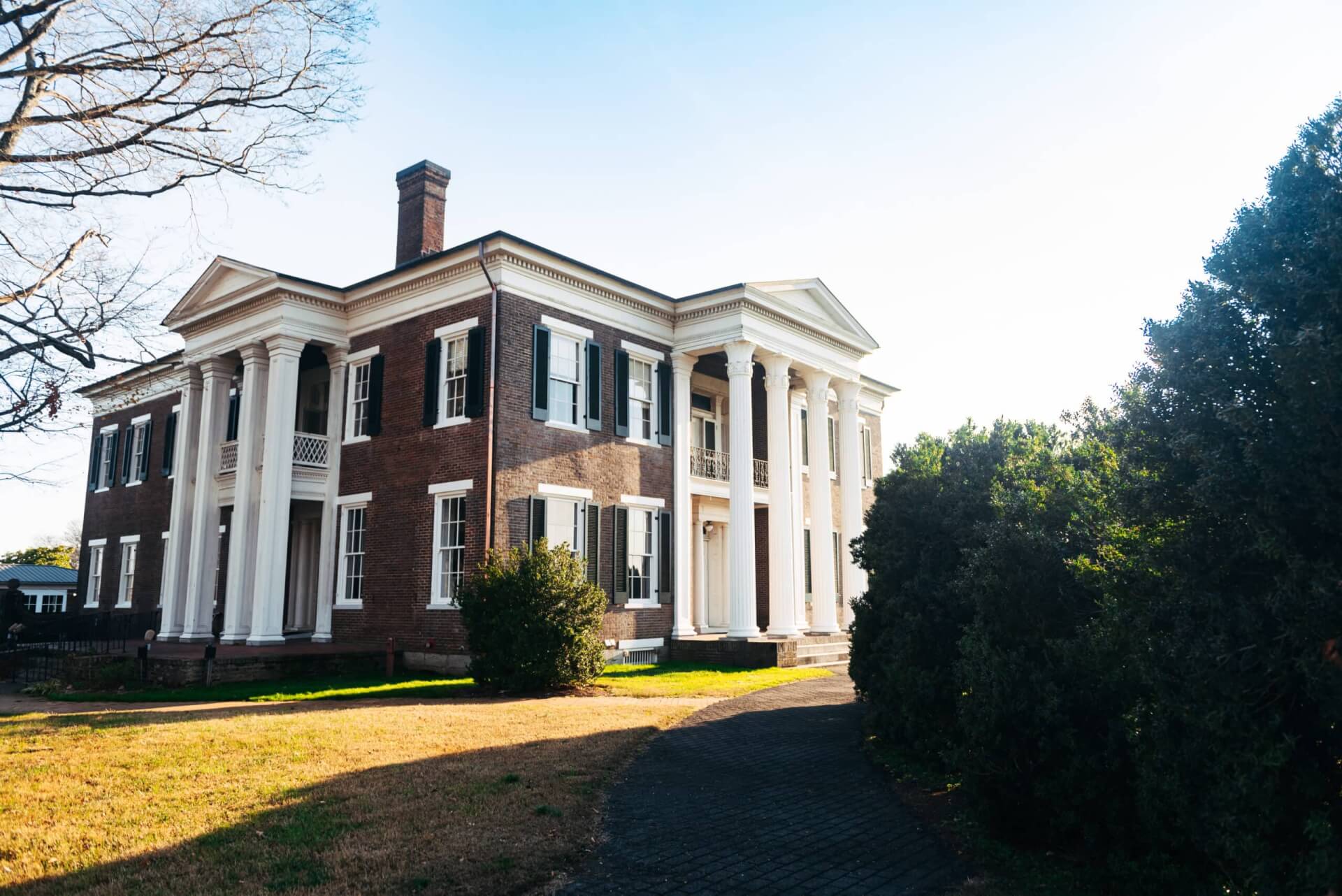 A stately brick mansion with white columns and a grand entrance, surrounded by lush greenery in Williamson County, Tennessee.