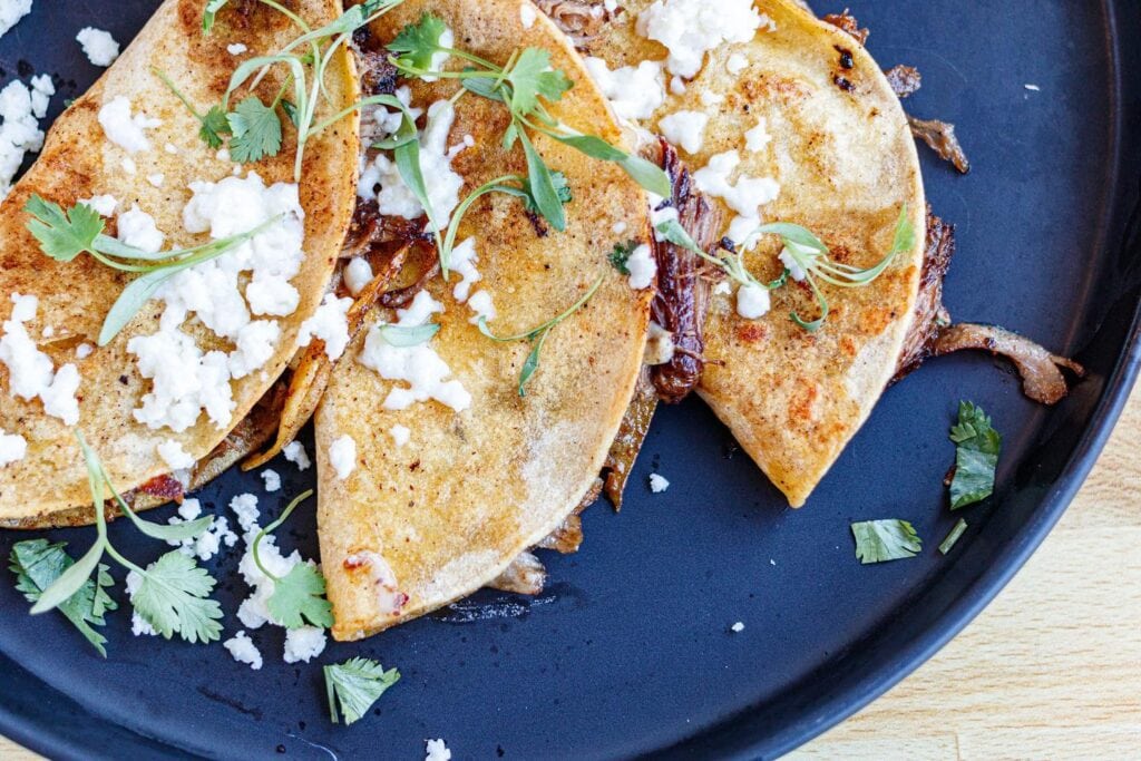 Three crispy corn tortillas filled with meat, onions, and topped with crumbled cheese and cilantro in Williamson County, Tennessee.