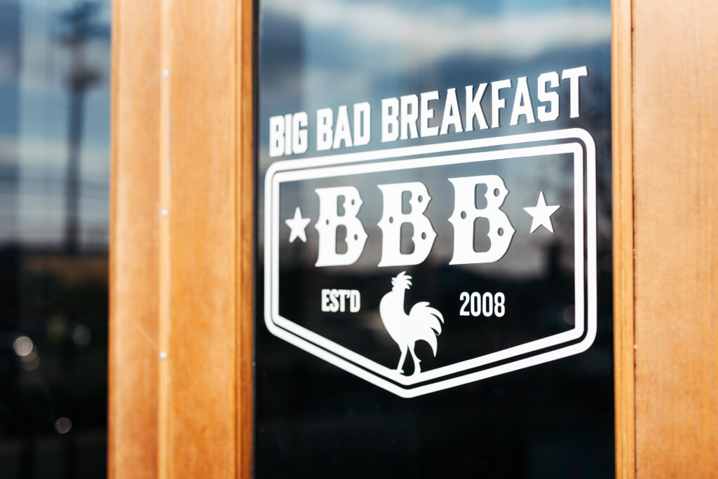 A sign on a glass door advertises 'Big Bad Breakfast' with a rooster logo in Williamson County, Tennessee.