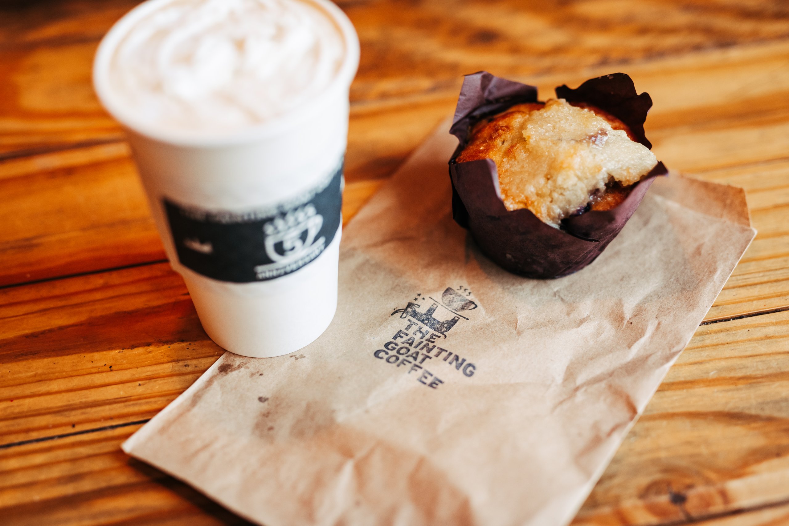A steaming cup of coffee and a blueberry muffin on a wooden table in Williamson County, Tennessee.